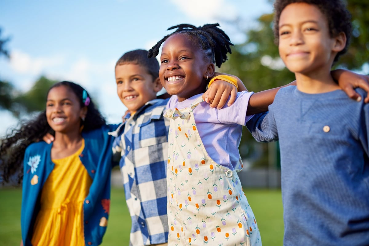 Happy tweens in a row jumping together at a park at sunset, laughing and enjoying being active together outdoors