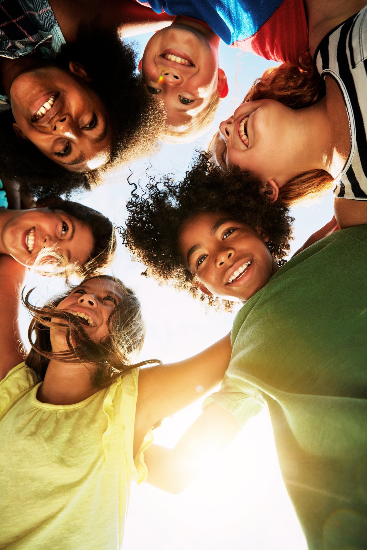 Portrait of a group of diverse and happy kids huddled together on a bright day outside